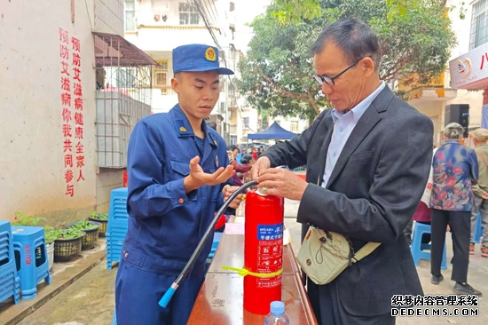 宣传人员向居民讲解灭火器的使用方法。